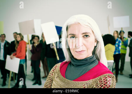 Portrait of serious woman with protesters in background Stock Photo