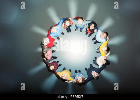 Business people forming huddle around bright light Stock Photo