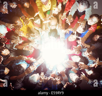 Diverse crowd reaching for bright light Stock Photo