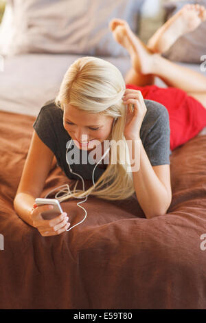 Woman listening to mp3 player on bed Stock Photo