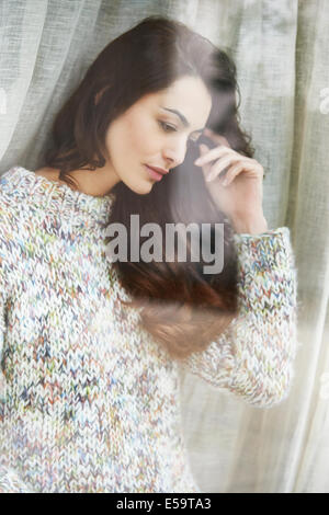 Woman standing by window Stock Photo