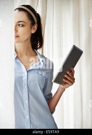 Woman using digital tablet by window