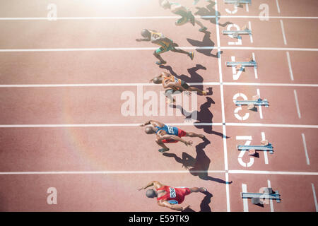 Runners taking off from starting blocks on track Stock Photo