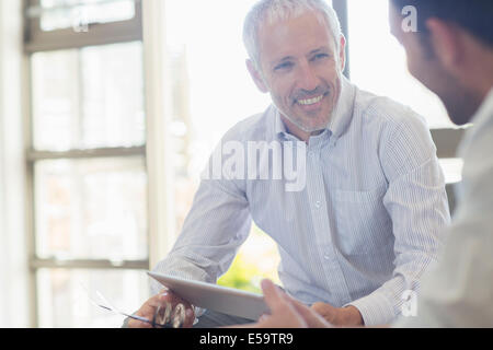 Businessmen laughing together in office Stock Photo
