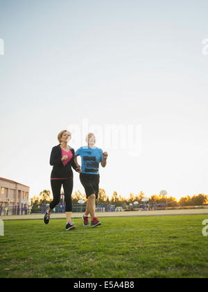 Older couple jogging together in urban park Stock Photo