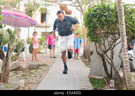 Older man playing hopscotch in town square Stock Photo