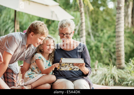 Older Caucasian woman and grandchildren looking at photo album Stock Photo