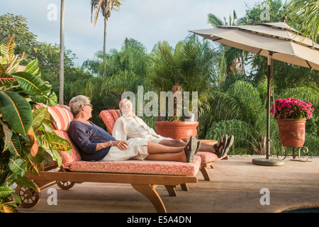 Older Caucasian couple relaxing by pool Stock Photo