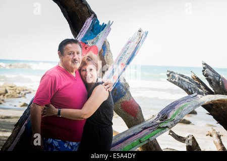 Hispanic couple hugging on beach Stock Photo