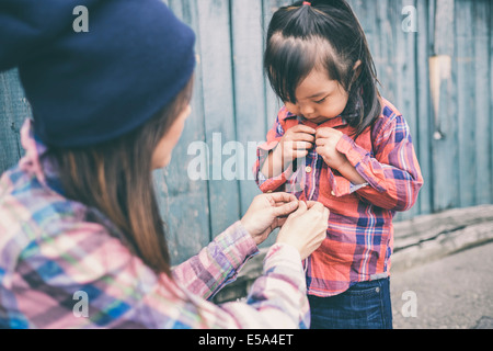 Asian mother and her young daughter together. The little girl is eating