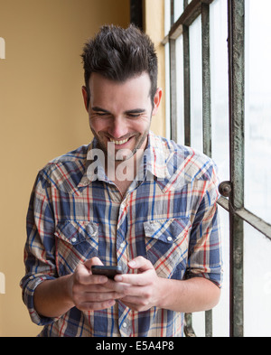 Caucasian man using cell phone by window Stock Photo