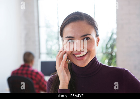 Mixed race architect talking on cell phone in office Stock Photo