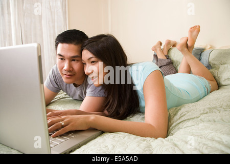 Chinese couple using laptop on bed Stock Photo