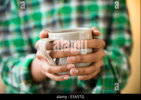 Mixed race woman holding cup of coffee Stock Photo