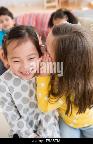 Girl whispering into friend's ear Stock Photo