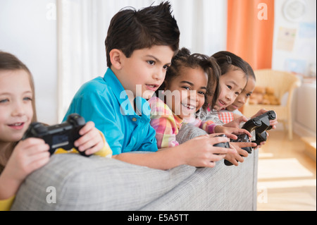 Children playing video games on sofa Stock Photo