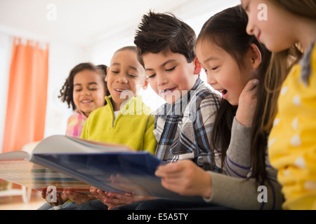 Children reading together in living room Stock Photo