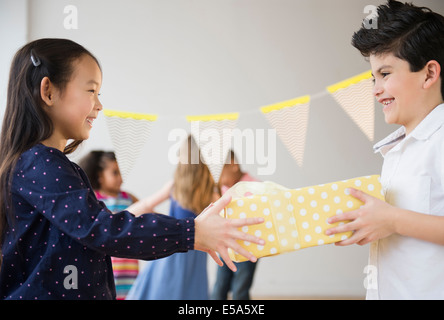 Boy giving girl birthday present at party Stock Photo