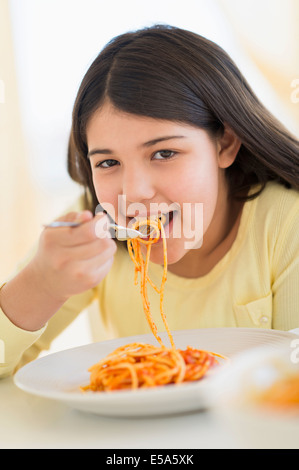Hispanic girl eating plate of pasta Stock Photo