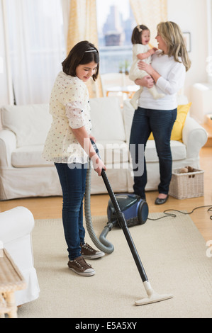 Hispanic girl vacuuming living room Stock Photo