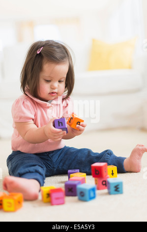 Hispanic toddler with Down syndrome playing with blocks Stock Photo
