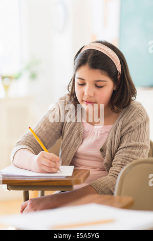 Hispanic girl taking notes in classroom Stock Photo