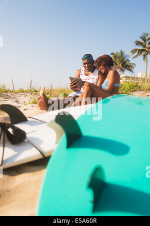 Couple using digital tablet on beach Stock Photo