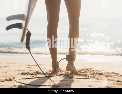 Woman tethered to surfboard on beach Stock Photo