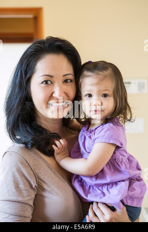 Mother holding daughter in kitchen Stock Photo