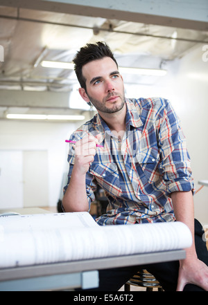 Caucasian architect designing blueprints in office Stock Photo