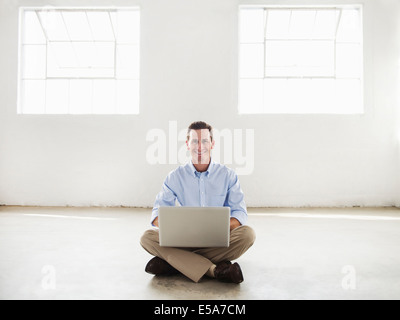 Caucasian businessman using laptop in empty office Stock Photo