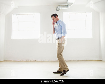 Caucasian businessman talking on cell phone in empty office Stock Photo