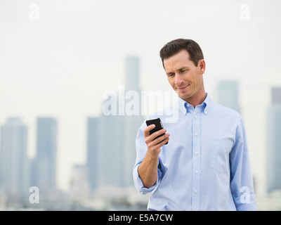 Caucasian businessman using cell phone on urban rooftop Stock Photo