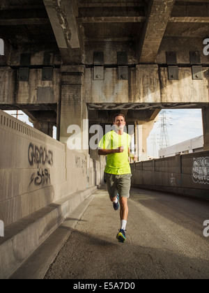 Caucasian man running in urban tunnel Stock Photo