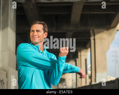 Caucasian man stretching in urban tunnel Stock Photo