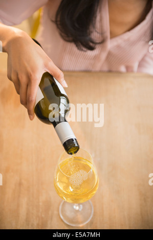 Mixed race woman pouring glass of wine Stock Photo