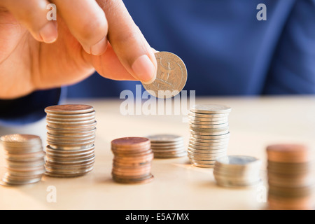 Mixed race woman stacking coins Stock Photo