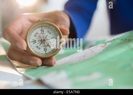 Mixed race woman holding map and compass Stock Photo