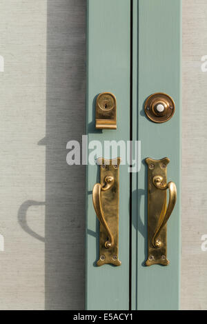 Close up detail of brass fittings on a double door, handles, yale lock and bell push. Stock Photo