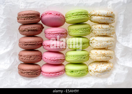 Food: multicolored macarons assortment, arranged on white crumpled paper, isolated on white background Stock Photo