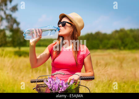 Active woman with bike drinking cold water, Debica, Poland Stock Photo