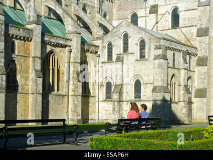 Two women sitting on bench, outside Chichester Cathedral, West Sussex, England UK Stock Photo