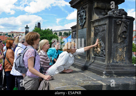 Touching the bas relief at the base of the statue of St John Napomuk on Charles bridge apparently brings to good luck, Prague. Stock Photo