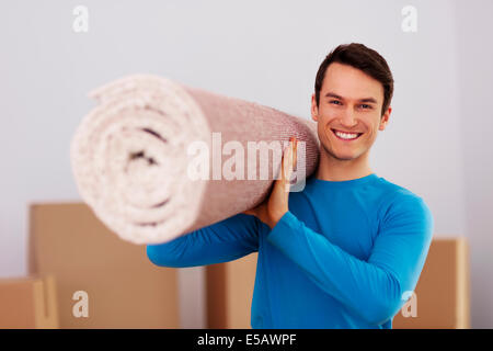 Happy male carrying a carpet in new home Debica, Poland Stock Photo