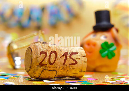 champagne cork marked with year 2015 in front of pig with cloverleaf as symbol for good luck Stock Photo