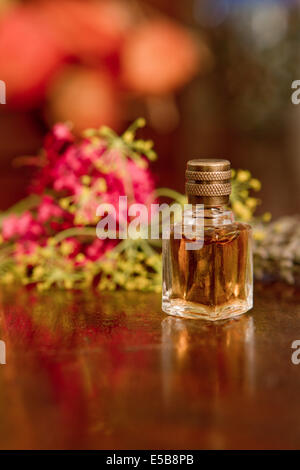 Still life of perfume bottle with flowers on wooden surface. Stock Photo