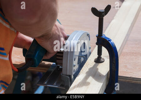 Carpenter doing DIYcutting wood with an electric circular saw powertool. England, UK, Britain, Stock Photo