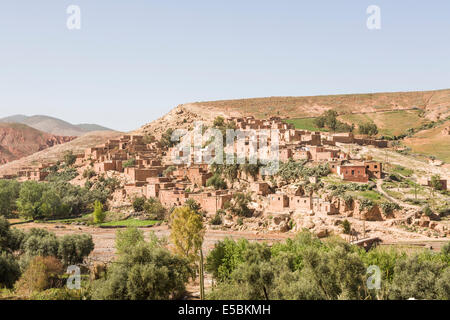 Red brick houses, some ruined, of a Berber village built on a hillside in the High Atlas Mountains, Morocco Stock Photo