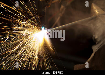 A metal fabricator utilizing a torch to heat up a piece of metal in order to shape it. Stock Photo