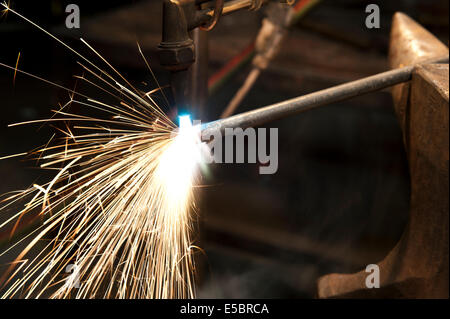 A metal fabricator utilizing a torch to heat up a piece of metal in order to shape it. Stock Photo